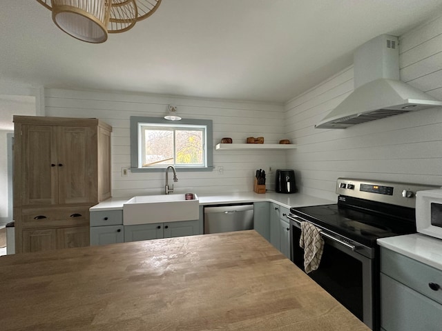 kitchen featuring wood walls, sink, gray cabinets, extractor fan, and appliances with stainless steel finishes