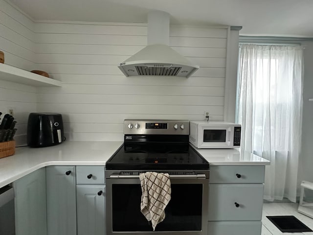 kitchen featuring stainless steel appliances, wood walls, and extractor fan