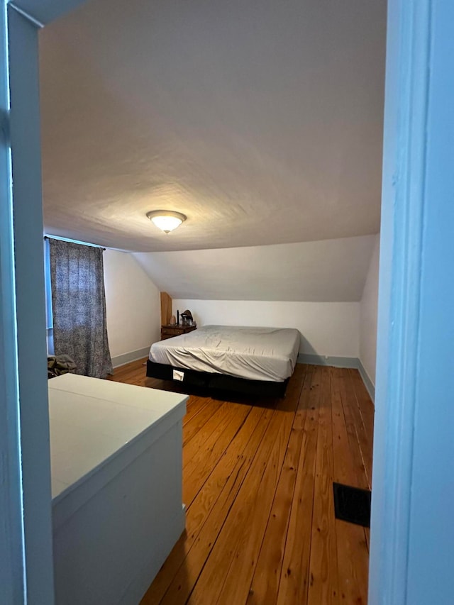 bedroom featuring hardwood / wood-style flooring and lofted ceiling