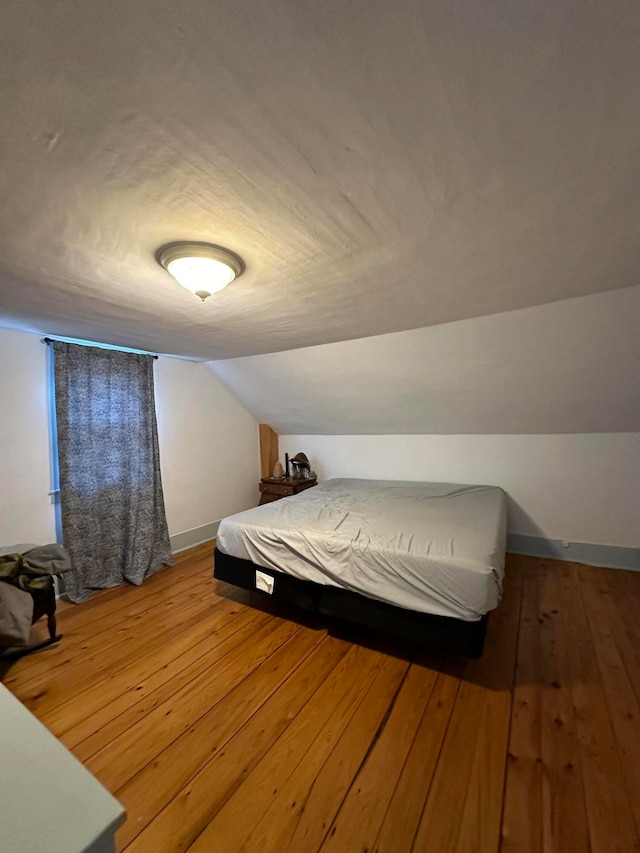 bedroom featuring wood-type flooring and vaulted ceiling