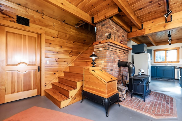 interior space with concrete flooring, a wood stove, and wooden walls