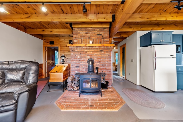 living room featuring track lighting, wood ceiling, beam ceiling, a wood stove, and wood walls