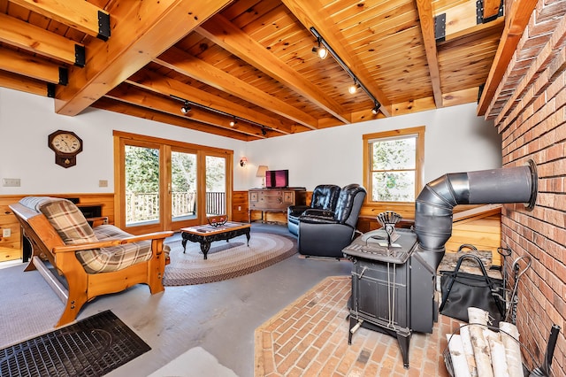 living room with beamed ceiling, rail lighting, plenty of natural light, and wooden walls