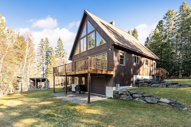 back of house featuring a garage, a lawn, and a wooden deck