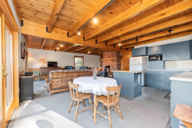 dining area with wooden walls, beam ceiling, a wood stove, and wood ceiling