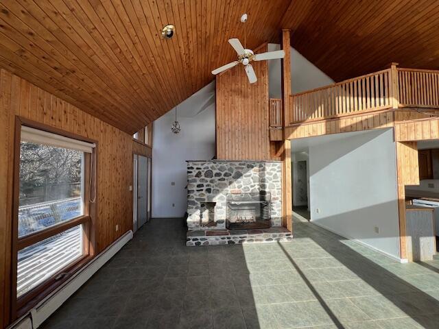 unfurnished living room featuring ceiling fan, high vaulted ceiling, a fireplace, and a baseboard heating unit