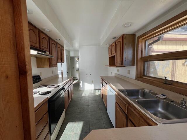 kitchen with white dishwasher, dark tile patterned flooring, electric stove, and sink