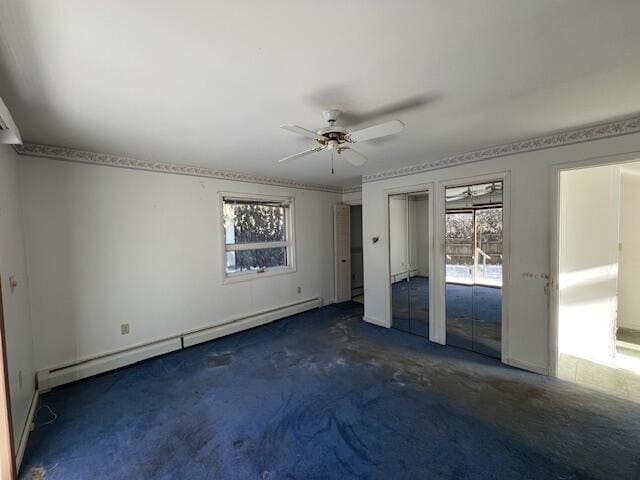 unfurnished bedroom with baseboard heating, two closets, ceiling fan, and dark colored carpet