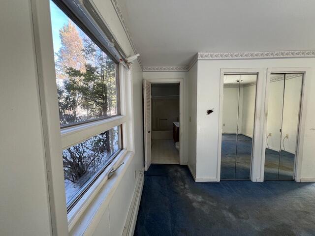 hall with dark colored carpet and a baseboard radiator