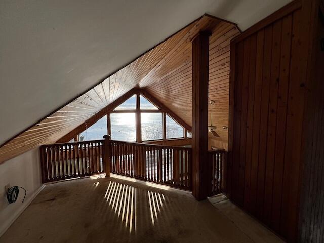 bonus room with ceiling fan, vaulted ceiling, carpet floors, and wood walls