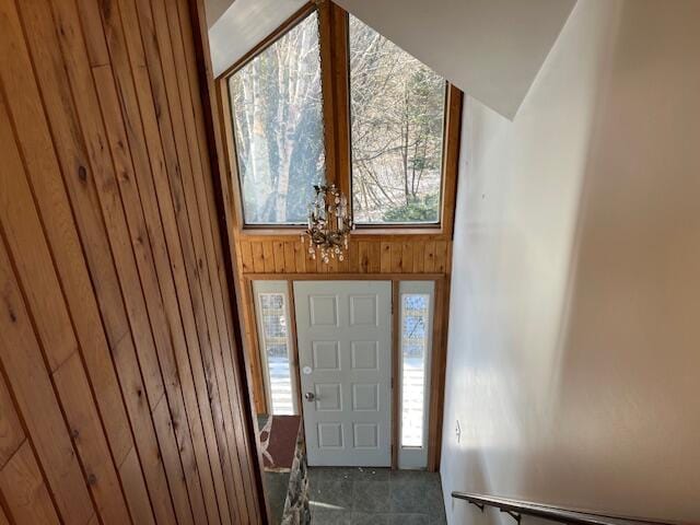 entrance foyer with a wealth of natural light, wooden walls, and lofted ceiling