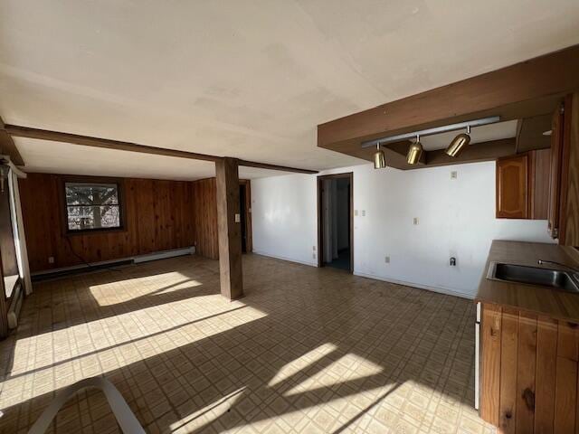 basement featuring sink, wooden walls, and a baseboard radiator