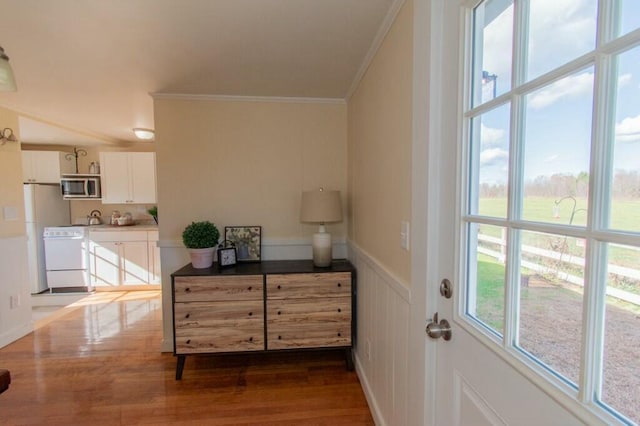 entryway with crown molding, dark wood-style flooring, and wainscoting