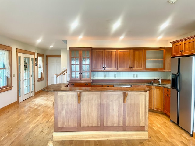 kitchen featuring french doors, stainless steel appliances, a kitchen bar, a kitchen island, and light wood-type flooring