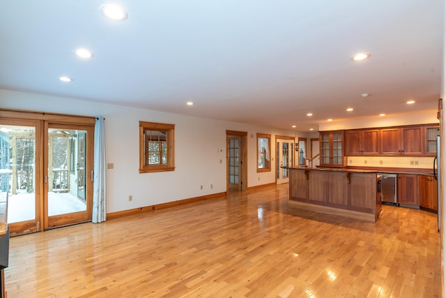 kitchen with a breakfast bar area, dishwasher, a kitchen island, and light wood-type flooring