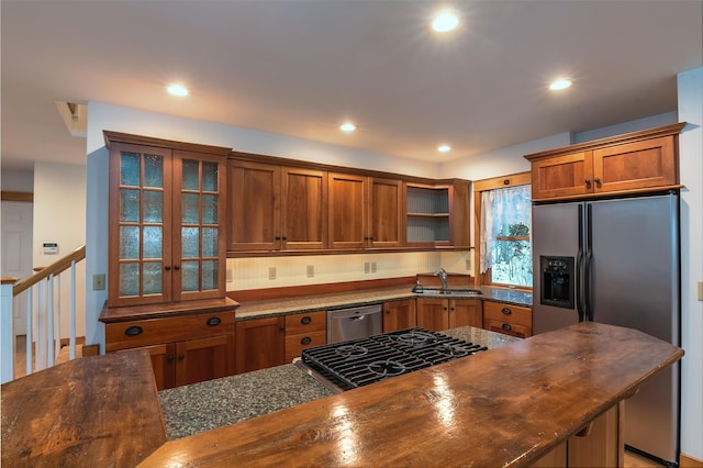 kitchen with sink, appliances with stainless steel finishes, and dark stone counters