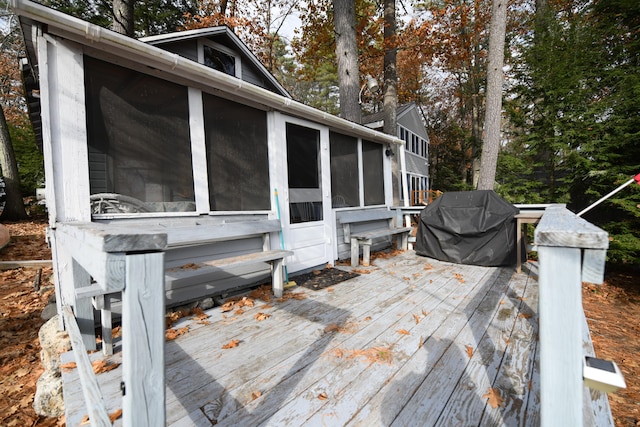 wooden terrace featuring a sunroom and a grill