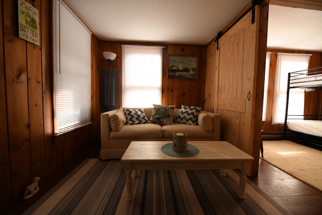 living room featuring a barn door, wooden walls, and carpet flooring