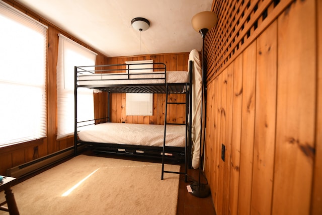 unfurnished bedroom featuring wooden walls, carpet floors, and a baseboard heating unit