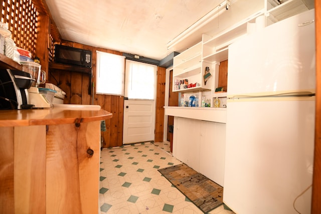 kitchen with wooden walls and white fridge