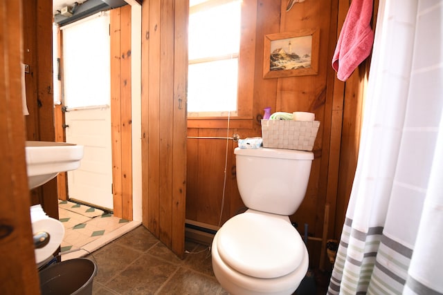 bathroom with toilet, wooden walls, and tile patterned floors