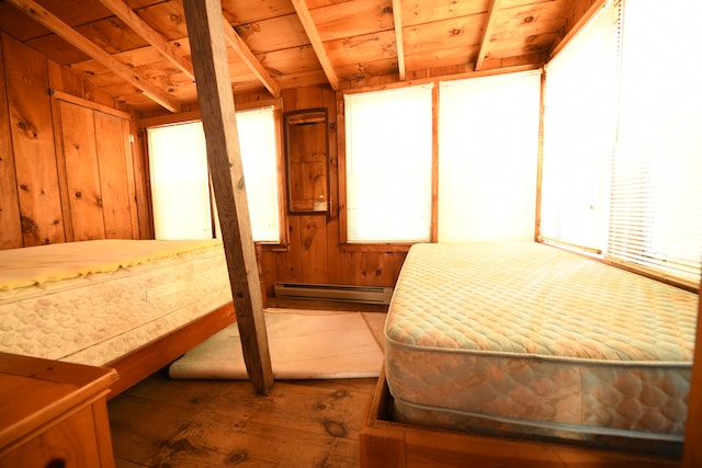 bedroom with baseboard heating, wood walls, and wood ceiling