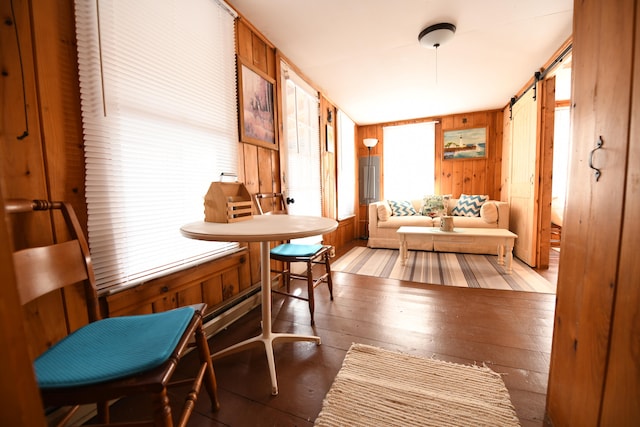 sitting room featuring wood walls, a barn door, and hardwood / wood-style flooring