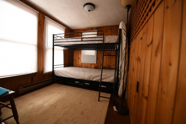 unfurnished bedroom with wooden walls, carpet flooring, and a baseboard radiator