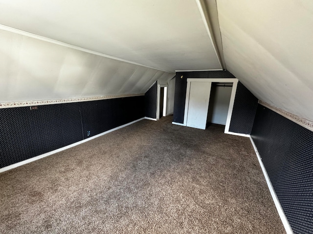 bonus room with dark carpet and vaulted ceiling