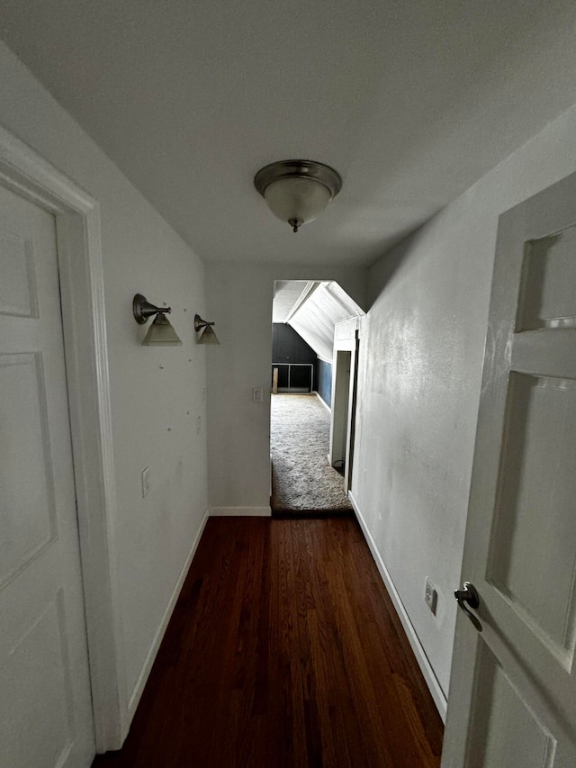 corridor featuring lofted ceiling and dark wood-type flooring