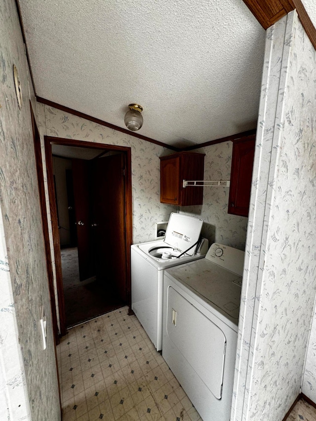 washroom featuring washing machine and dryer, crown molding, cabinets, and a textured ceiling