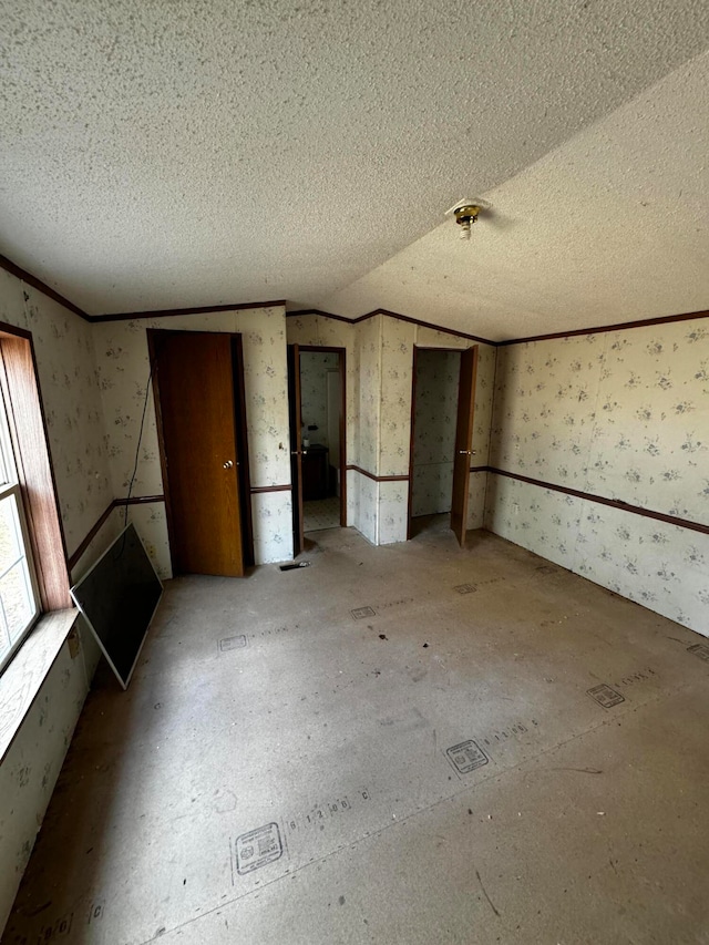 unfurnished bedroom with a textured ceiling and vaulted ceiling