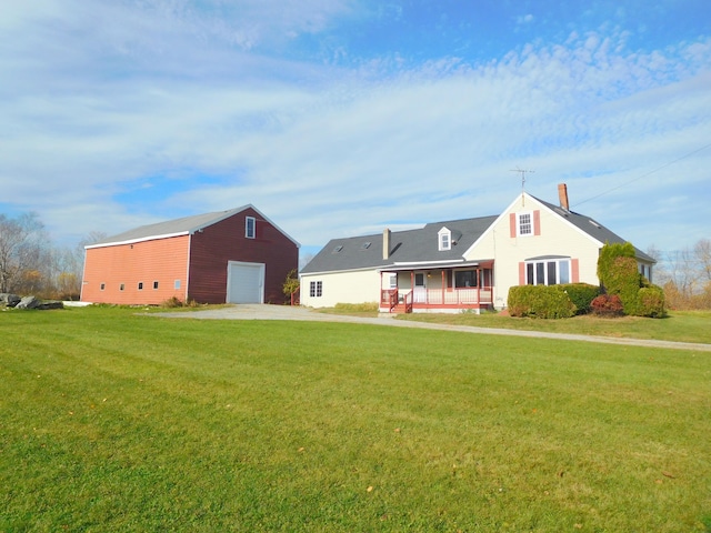 new england style home with covered porch, a garage, and a front yard