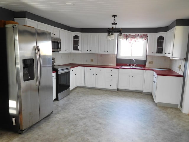 kitchen featuring white cabinetry, sink, decorative backsplash, hanging light fixtures, and stainless steel appliances