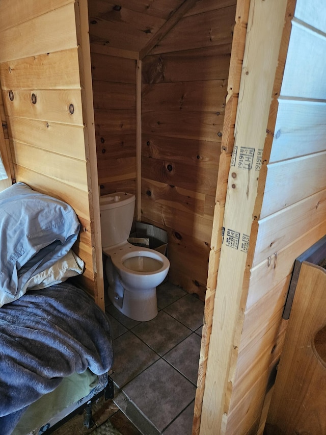 bathroom featuring tile patterned flooring, wooden walls, and toilet