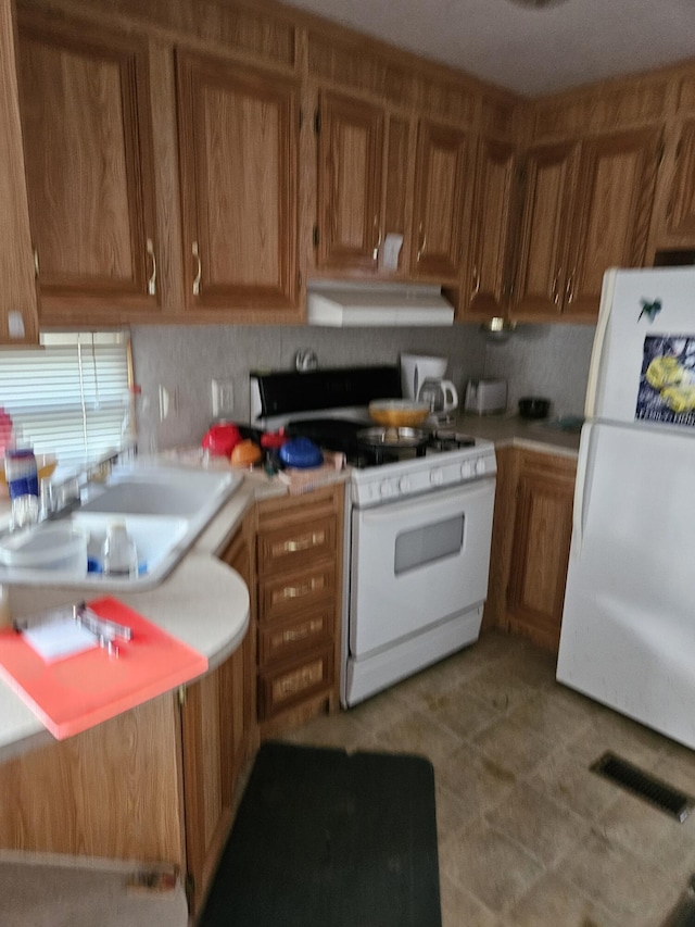 kitchen featuring white appliances, sink, and range hood