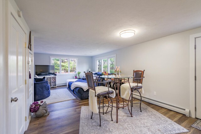 dining area featuring a textured ceiling, dark wood-type flooring, and a baseboard heating unit