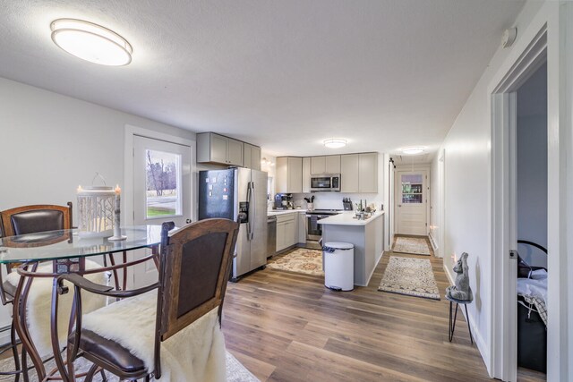 kitchen featuring dark hardwood / wood-style flooring, a textured ceiling, gray cabinets, a kitchen island, and appliances with stainless steel finishes