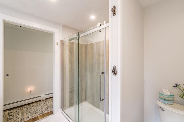 bathroom with hardwood / wood-style flooring, toilet, baseboard heating, and a shower with door