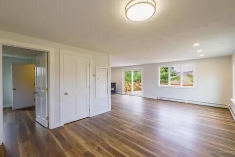 unfurnished living room with baseboard heating and dark wood-type flooring