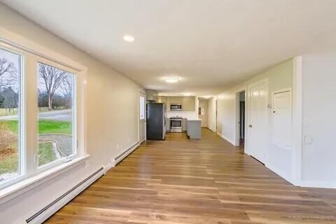 hallway with hardwood / wood-style flooring, plenty of natural light, and baseboard heating