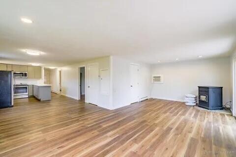 unfurnished living room with light hardwood / wood-style floors and a wood stove