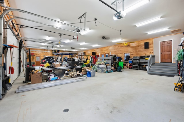 garage with a garage door opener and wooden walls