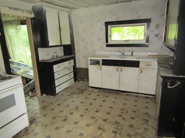 kitchen with white cabinetry, sink, and white electric stove