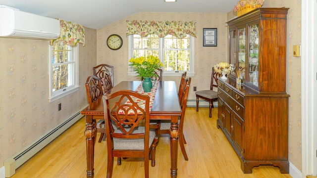 dining room with a wall mounted air conditioner, vaulted ceiling, light wood-type flooring, a baseboard radiator, and a healthy amount of sunlight