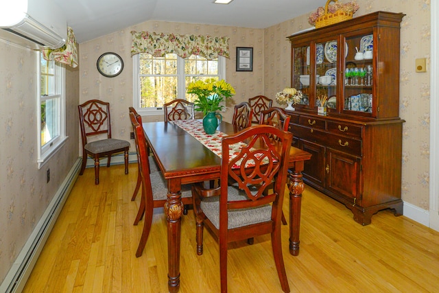 dining space with a baseboard heating unit, light wood-type flooring, an AC wall unit, and vaulted ceiling