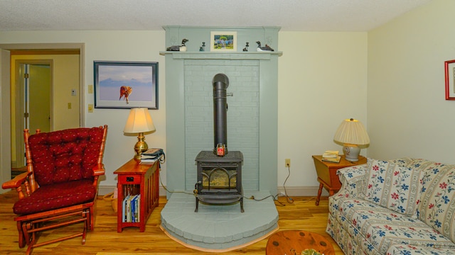 sitting room with wood-type flooring, a textured ceiling, and a wood stove