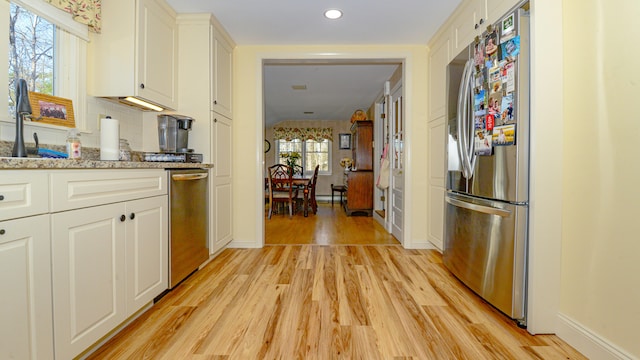 kitchen with a wealth of natural light, stainless steel refrigerator, and light hardwood / wood-style flooring