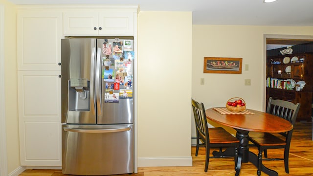 kitchen featuring white cabinets, stainless steel fridge, and light hardwood / wood-style floors