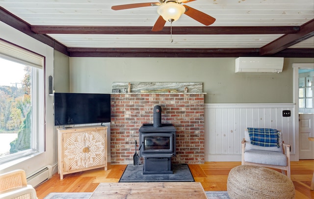 living room featuring a wood stove, beam ceiling, a wall mounted air conditioner, light hardwood / wood-style floors, and baseboard heating